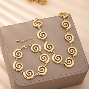 Gros plan détaillé de l'ensemble de bijoux dorés avec collier et bracelet à spirale