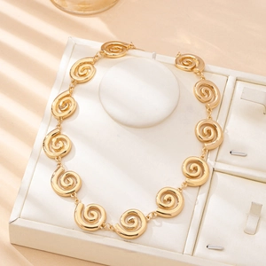Fashionable gold necklace with spiral textured metal rings on a white display stand