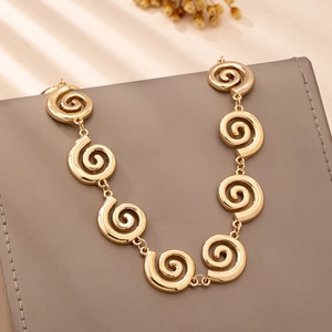 Detail of a gold spiral link necklace with polished finish on a textured background