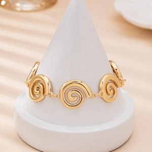 Elegant gold vortex link bracelet with spiral metallic plates on white display stand