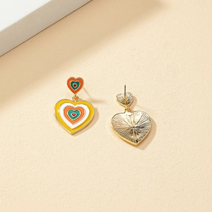 Boucles d'oreilles cœur multicouche en émail coloré avec base dorée sur fond neutre