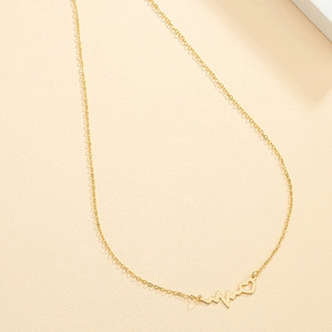 Golden heartbeat necklace with heart pendant and thin chain on beige background