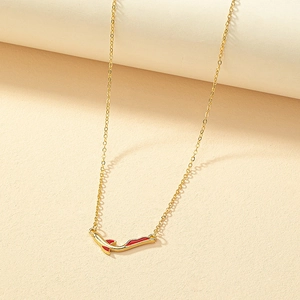 Collier baleine doré à l'émail rouge avec pendentif poisson sur fond texturé chaud