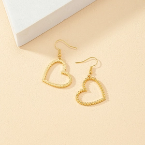 Detail of gold heart earrings showing textured finish and beaded metal textures