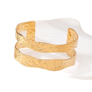 Elegant gold open cuff bracelet with a hammered texture and unique wavy edge design
