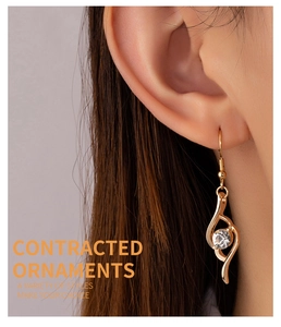 Close-up of golden teardrop earring with round diamond on model showing elegant curves