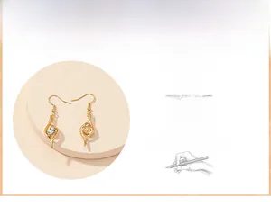 Macro detail of gold-plated dangle earrings featuring a clear round zircon in hollow design