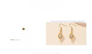 Detail of elegant gold-toned earrings featuring S-curved hooks and sparkling crystal drops