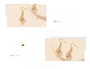 Detailed close-up of golden streamlined pendant earrings with sparkling round zircon stone