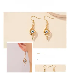 Detail of gold teardrop earrings featuring a crystal center and elegant ear hooks