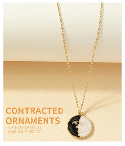 Detail of minimalist gold-plated necklace with black and white abstract face pendant