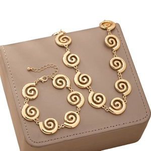 Parure de bijoux dorés avec collier et bracelet à motif spirale sur boîte cadeau