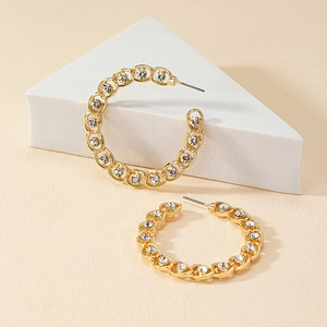 French style gold C-shape hoop earrings with white crystals on beige stone display