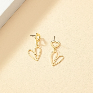 Elegant gold double hollow heart drop earrings on a textured minimalist background