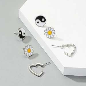 Detailed set of 6 stud earrings featuring yin yang, daisies, and silver hearts on white blocks