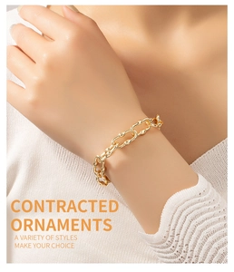 Close-up of minimalist gold-finish alloy chain bracelet on woman's wrist with knit sleeve