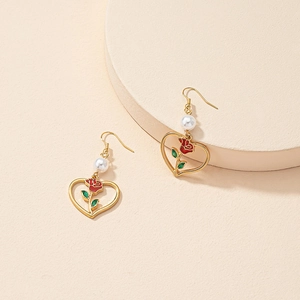 Orecchini a cuore dorati con rosa smaltata e perla su un elegante display di lusso
