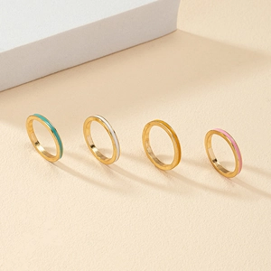 Set of four minimalist gold-plated rings with colorful enamel bands in pastel shades
