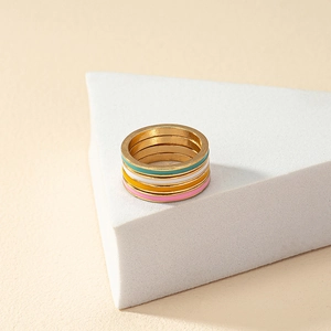 Colorful enamel spring ring set in gold finish on white geometric display stand