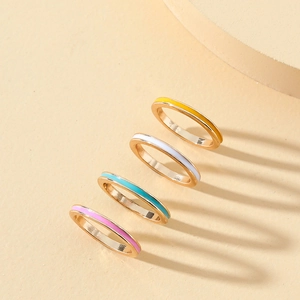 Close-up of four minimalist colorful enamel stackable rings in gold plated finish