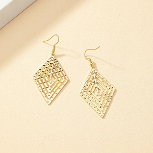 Detailed macro view of layered geometric diamond earrings with hammered gold finish