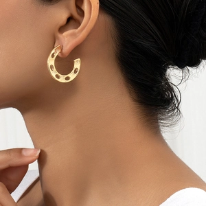 Golden C-shaped textured hollow earrings with brushed finish shown on a model