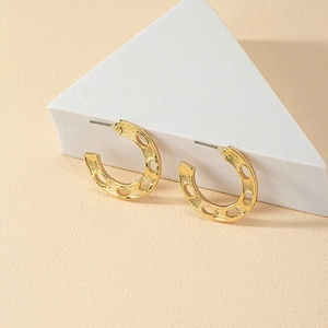 Detailed side view of golden C-shaped hoop earrings with textured hollow out design