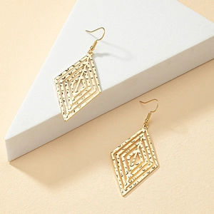 Gold hammered geometric rhombus drop earrings displayed on a minimalist white stand