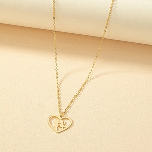 Goldfarbene Herzkette mit romantischer Kiss-Silhouette und hohlem Design auf beigem Grund