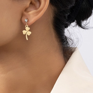 Boucles d'oreilles trèfle dorées avec strass présentées sur un mannequin féminin