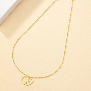 Minimalistische Goldkette mit Herzanhänger und Kuss-Silhouette auf beigem Grund