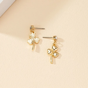 Détail de boucles d'oreilles trèfle doré avec texture brossée et incrustation de zircon