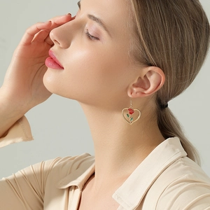 Elegante goldene Herzohrringe mit roter Rose und Emaille an einem Modemodell