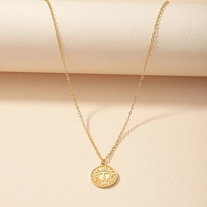 Gold sun coin pendant necklace with radial rays on warm textured artistic background
