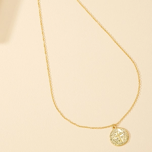 Macro detail of golden chain necklace featuring a vintage cross emblem coin pendant