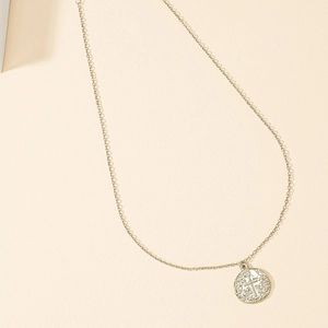 Detailed macro view of a vintage religious coin pendant with cross engraving on a slim chain