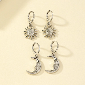 Detailed view of silver sun and moon earrings with artistic face reliefs on flat background