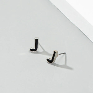 Detailansicht der silbernen J-Buchstaben-Ohrstecker mit schwarzer Emaille und Schatten