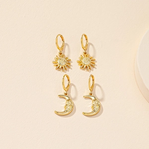 Detail view of gold sun and moon face earrings set with intricate facial engraving