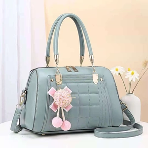 Detail of light blue quilted tote bag with lychee texture and pink ribbon charm