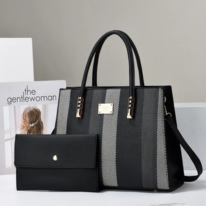 Detail shot of black and grey striped tote bag set with golden hardware and magazine