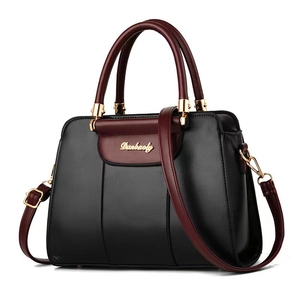 Minimalist black and burgundy leather shoulder bag with gold hardware on white background