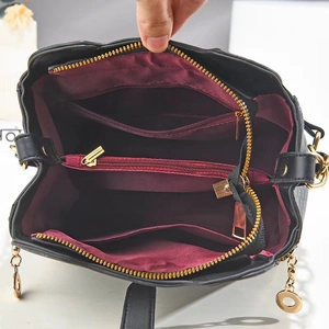 Detail of black tote bag interior with wine red lining and multiple zipper compartments
