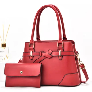 Detail of red PU leather handbag set featuring bow strap and golden buckle hardware