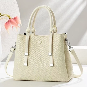 Close-up of cream woven texture tote bag with silver hardware on a minimalist background