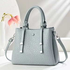 Detail of grey-blue woven texture handbag with silver metal accents and strap