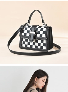Close-up of black and white checkered crossbody bag with leather trim and silver buckle