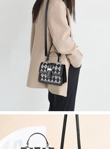 Macro detail of houndstooth crossbody bag with silver buckle and adjustable strap