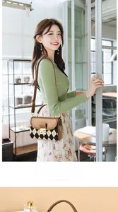 Detail of a vintage-style argyle shoulder bag featuring brown leather trim and metal lock