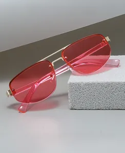 Detailed shot of half-rim sunglasses with red gradient lenses on a stone display